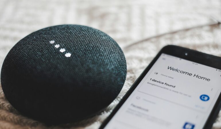 Turned-on charcoal Google Home Mini and smartphone photo