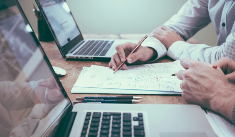 person holding a pencil near laptop