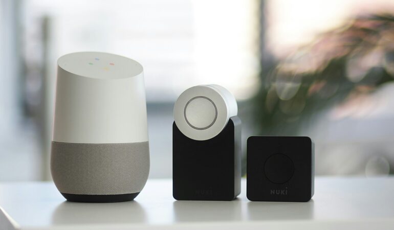 white and gray Google smart speaker and wo black speakers