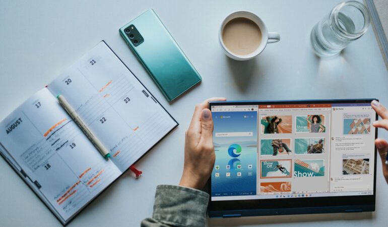 person using Windows 11 computer beside white ceramic mug on white table