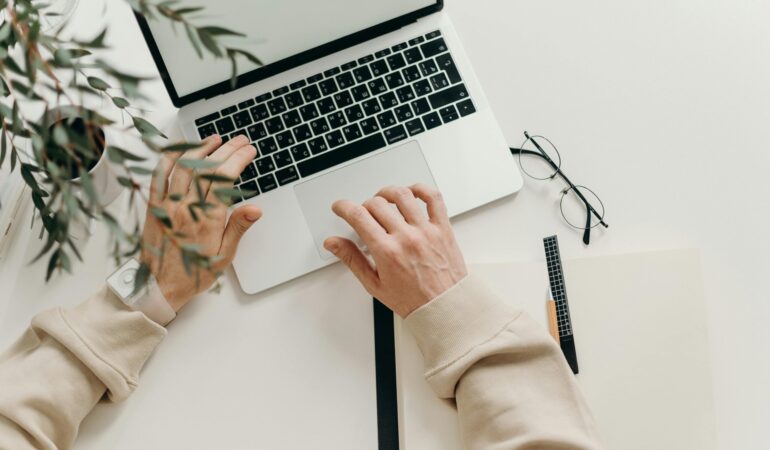 Free An overhead view of a person working on a laptop in a minimalist home office setting. Stock Photo